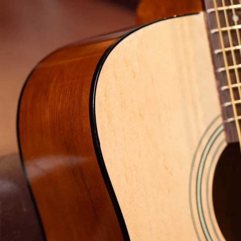 Close-up of an acoustic guitar's body, showing the light top, dark binding, and part of the rosette near the soundhole. ขายราคาพิเศษ
