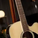 Close-up of an acoustic guitar neck and body, warm wood tones and strings visible near the soundhole ขายราคาพิเศษ