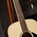 Close-up of an acoustic guitar neck with frets and strings over a light-colored body. ขายราคาพิเศษ