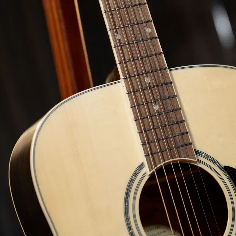 Close-up of an acoustic guitar's laminated top, soundhole, and fretboard with steel strings and frets visible on a wooden neck. ขายราคาพิเศษ