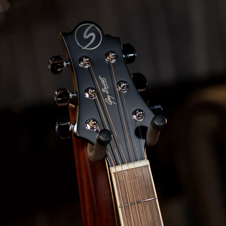 Close-up of a guitar headstock with six chrome tuning pegs and strings against a dark background, angled to one side. ขายราคาพิเศษ