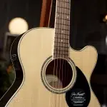 Close-up of a natural wood acoustic guitar with a cutaway, focusing on the soundhole, rosette, and neck detail. ขายราคาพิเศษ