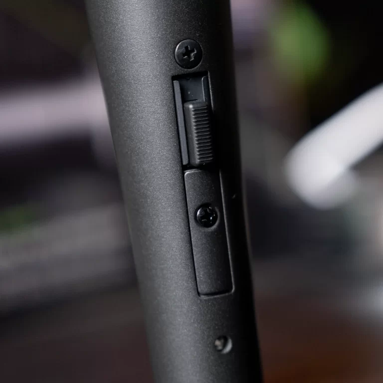 Close-up of a small vertical slider switch on a matte black cylindrical device, with two screws nearby. ขายราคาพิเศษ