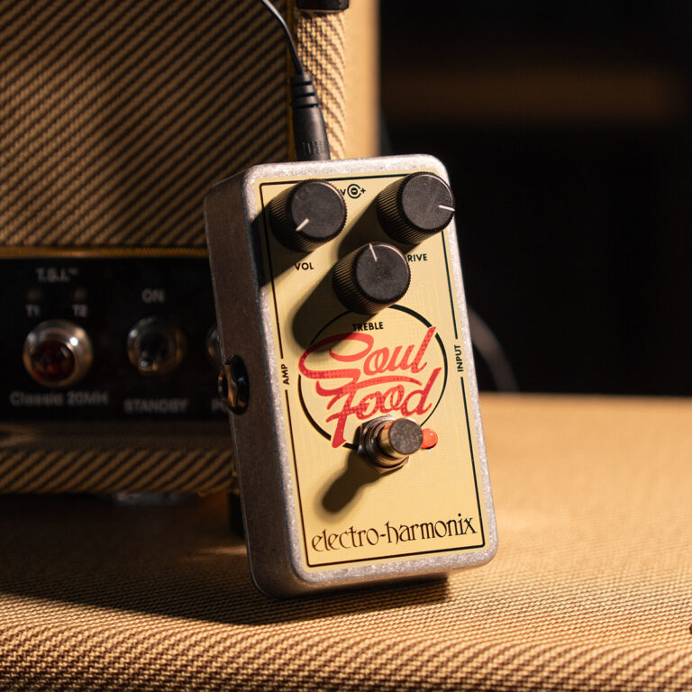 Electro-Harmonix Soul Food overdrive guitar pedal with three knobs on a beige faceplate, plugged in and resting on a textured amp cloth. ขายราคาพิเศษ