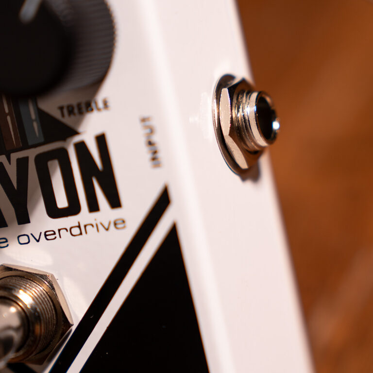 Close-up of a white guitar effects pedal showing an input jack, knob, and the word 'overdrive'.] ขายราคาพิเศษ