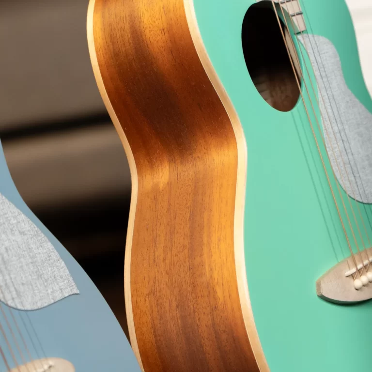Close-up of two acoustic guitars with teal and blue bodies, showing wood necks and strings close to the soundhole edge. ขายราคาพิเศษ