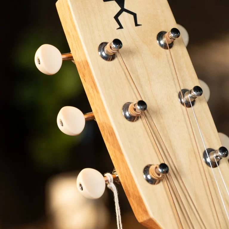 Close-up of a guitar headstock showing tuning pegs, strings, and wooden neck. ขายราคาพิเศษ