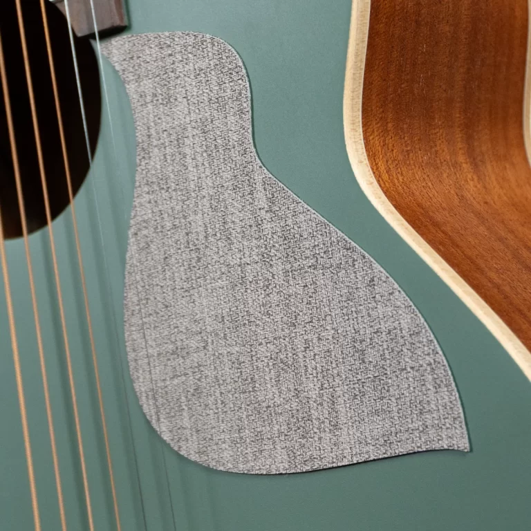 Close-up of a teal acoustic guitar body showing a large grey textured patch and natural wood edge. ขายราคาพิเศษ