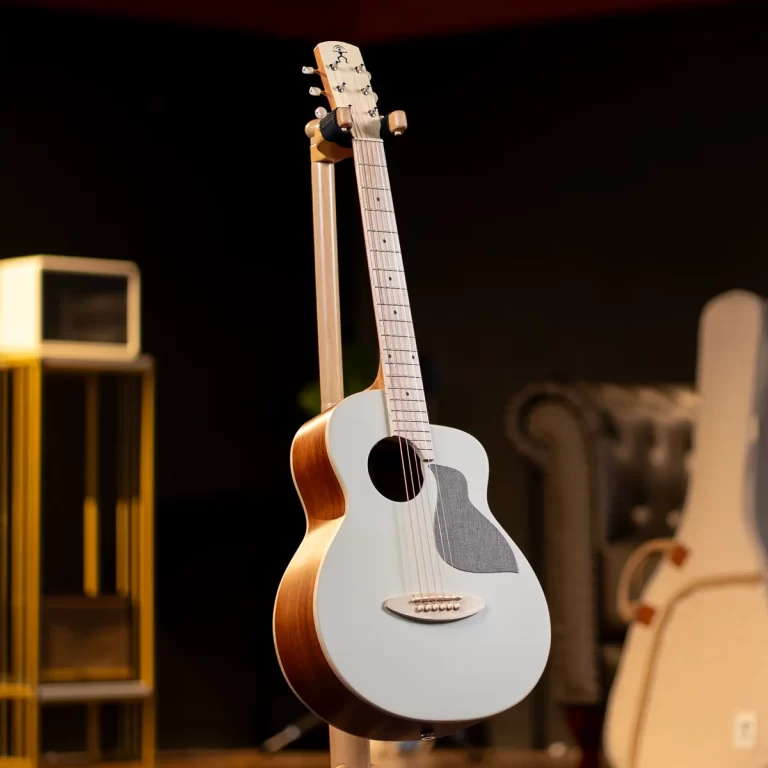 Acoustic guitar on a stand in a dim studio, warm lighting, with other equipment blurred in the background. ขายราคาพิเศษ