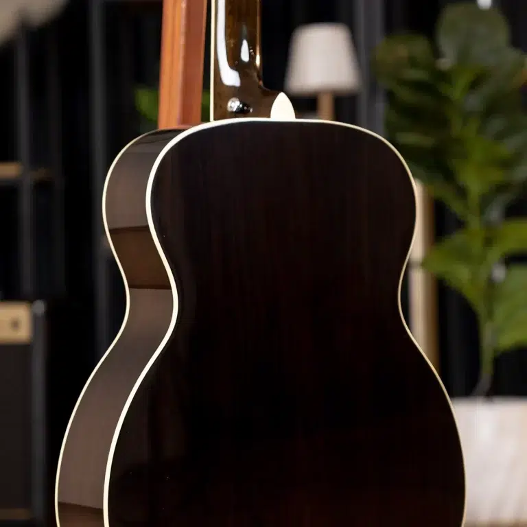 Back view of a dark wood acoustic guitar with cream binding in a studio setting ขายราคาพิเศษ