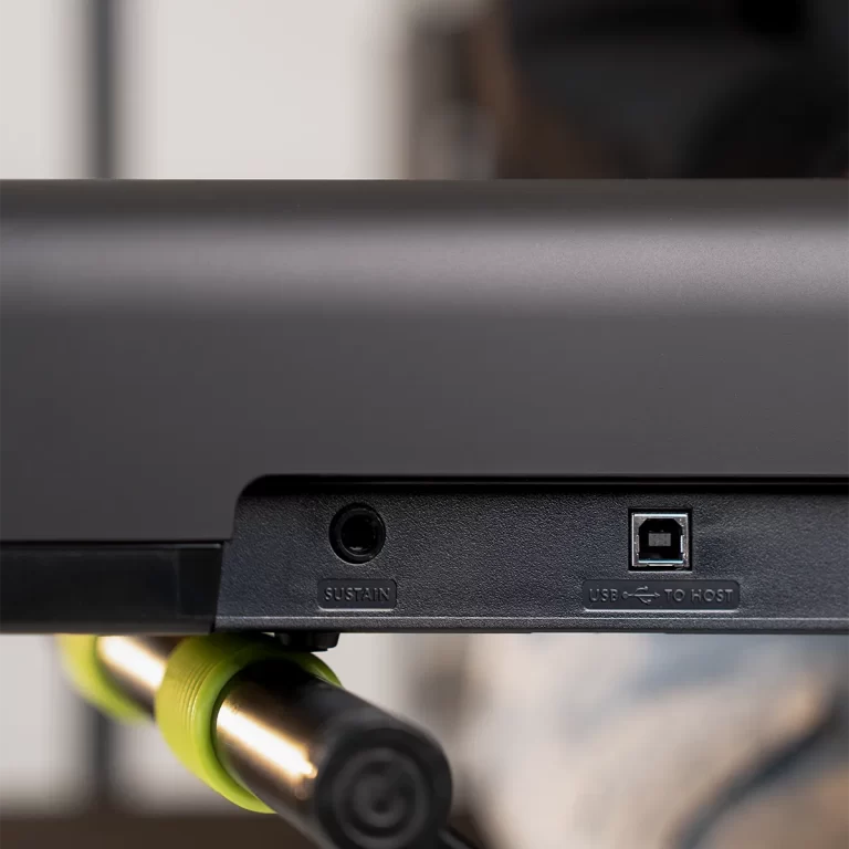 Back edge of a device showing a USB-to-host port and a labeled SUSTAIN input; a bright green clamp attaches a rod below. ขายราคาพิเศษ