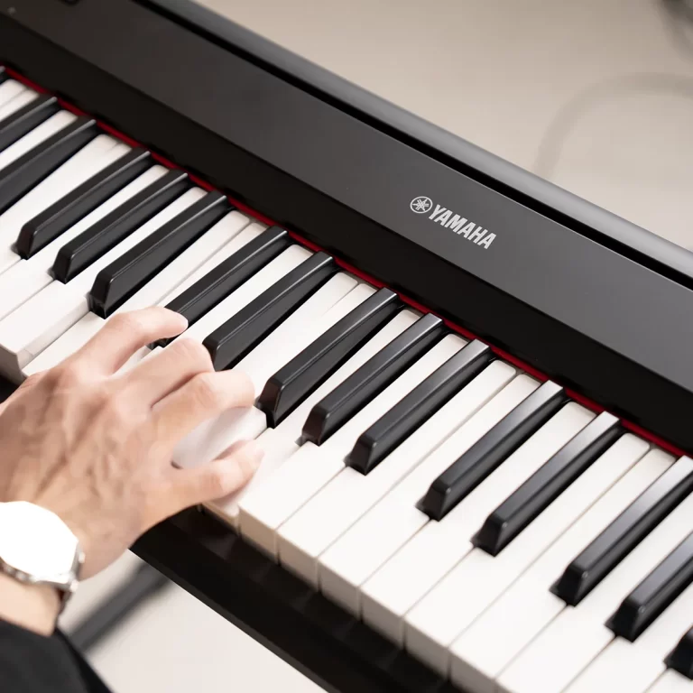 Close-up of a hand pressing keys on a Yamaha digital piano with black and white keys visible. ขายราคาพิเศษ