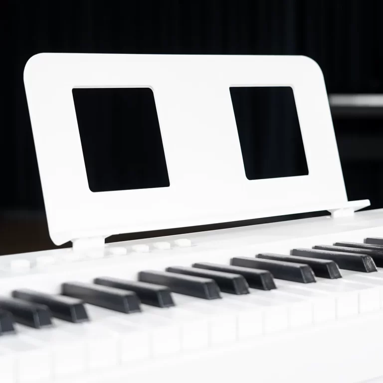 Close-up of a white piano with a contemporary stand behind the keys and black keys in the foreground ขายราคาพิเศษ