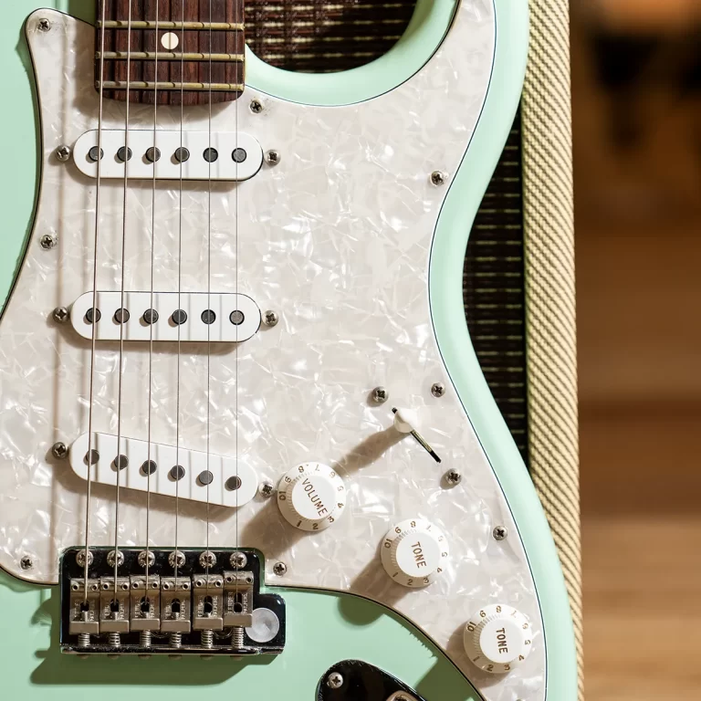 Mint green electric guitar close-up with white pearloid pickguard, three pickups, and tuning-bridge hardware. ขายราคาพิเศษ
