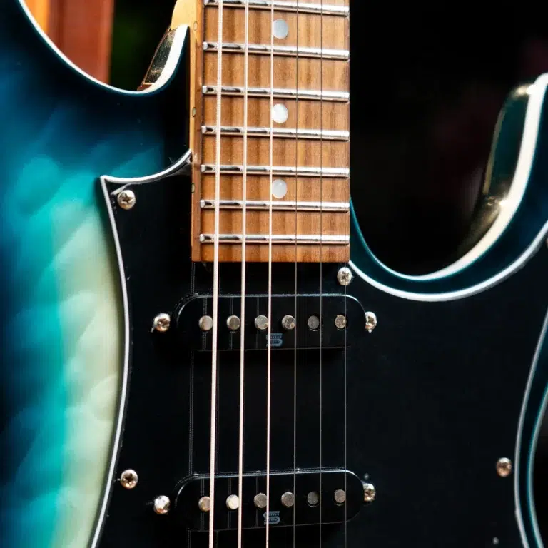 Close-up of a teal electric guitar neck showing the fretboard, strings, and pickups ขายราคาพิเศษ
