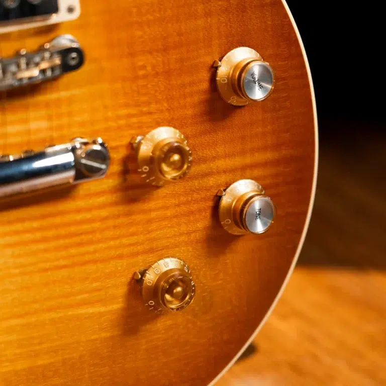 Close-up of a sunburst electric guitar body with four amber control knobs (volume and tone) and chrome hardware magnified on a warm wooden finish ขายราคาพิเศษ