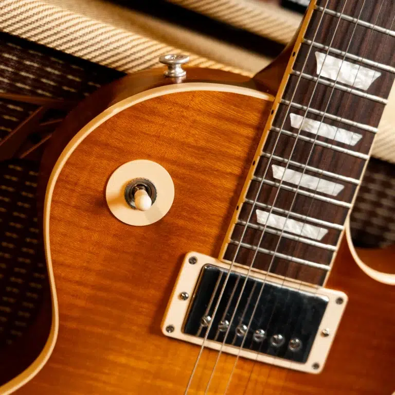 Close-up of a sunburst electric guitar body with a single humbucker pickup and gleaming strings. ขายราคาพิเศษ