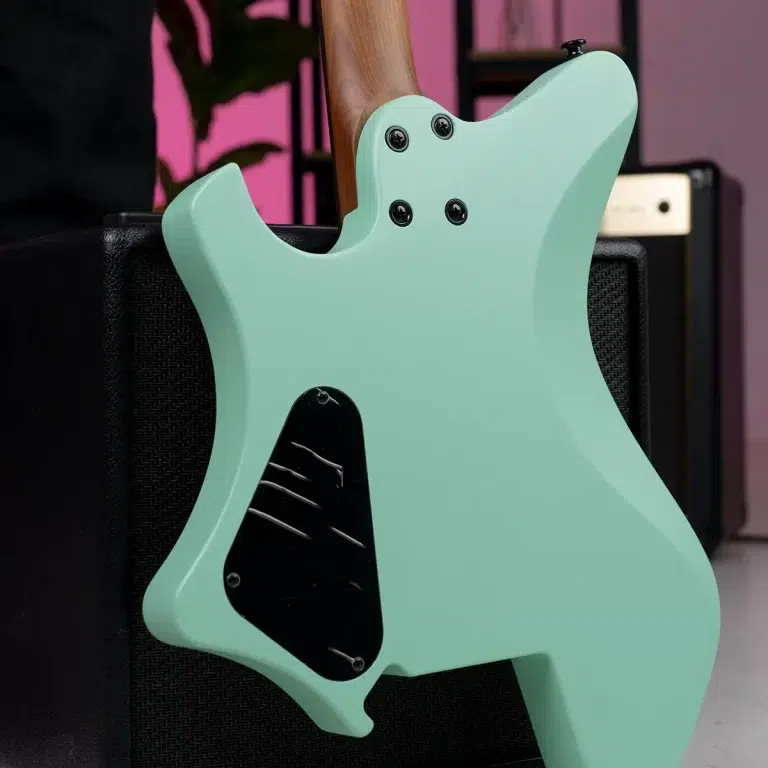 Back view of a mint green electric guitar leaning on a black amplifier, showing the rear control cavity cover and neck joint details. ขายราคาพิเศษ