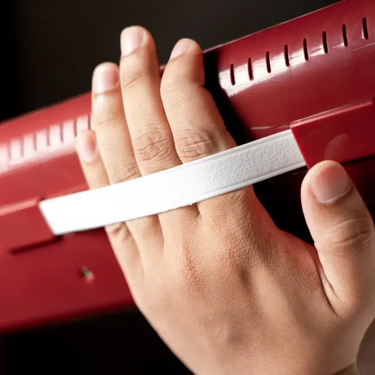Close-up of a small hand pressing a white measuring strip against a red ruler to measure length. ขายราคาพิเศษ