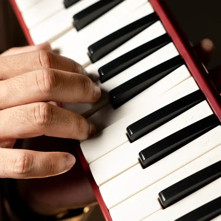 Close-up of hands playing a piano, with black and white keys in view. ขายราคาพิเศษ