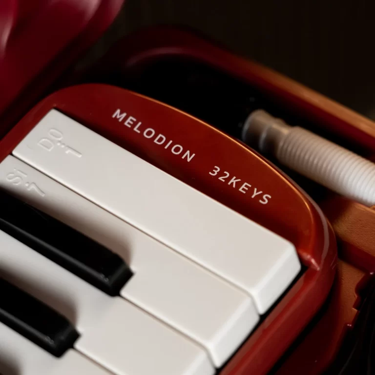 Close-up of a red Melodion instrument with white keys visible, labeled '32 KEYS' ขายราคาพิเศษ