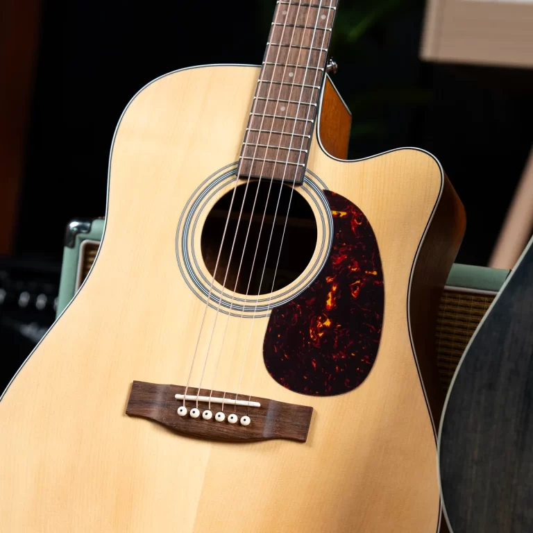 Light-colored acoustic guitar with six strings, sound hole, and dark tortoiseshell pickguard on a natural wood body. ขายราคาพิเศษ