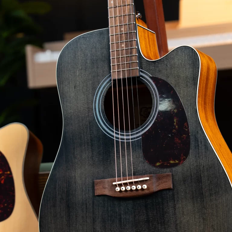 Close-up of a dark gray acoustic guitar showing the soundhole, rosette, strings, and wooden bridge. ขายราคาพิเศษ