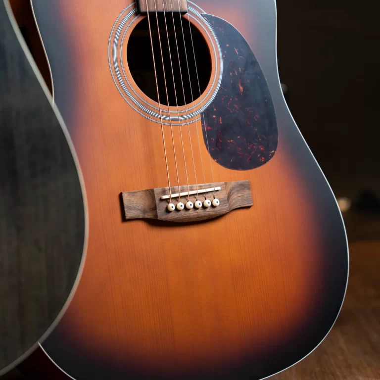 Close-up of a sunburst acoustic guitar showing the soundhole, strings, and wooden bridge with a tortoiseshell pickguard nearby ขายราคาพิเศษ