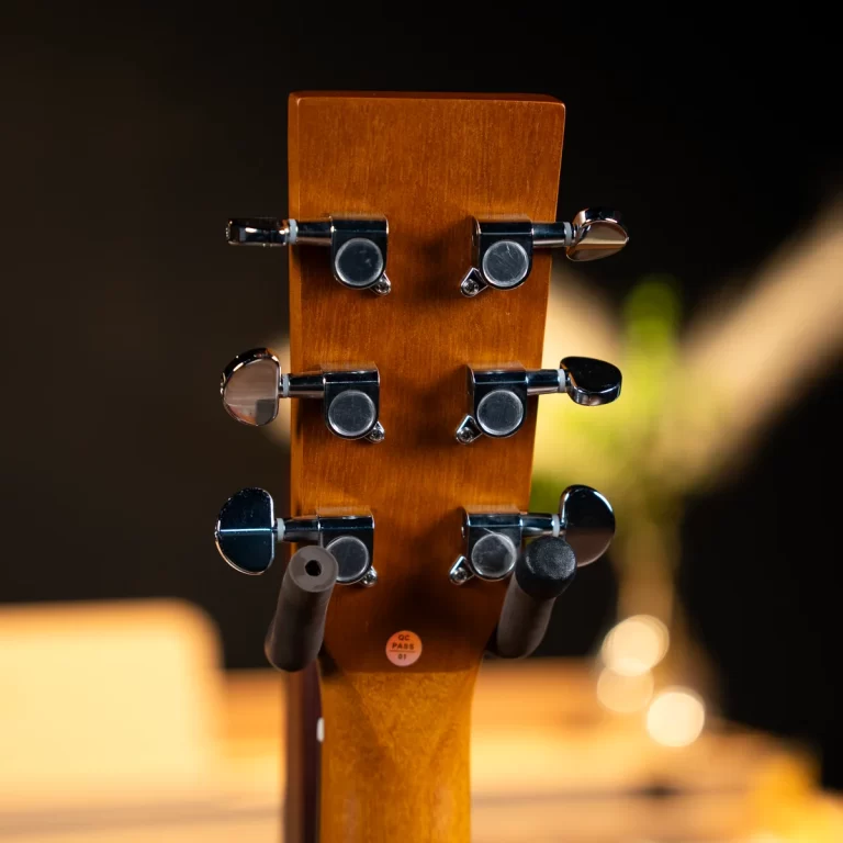 Close-up of a guitar headstock with six chrome tuning pegs on a warm brown wooden neck. ขายราคาพิเศษ