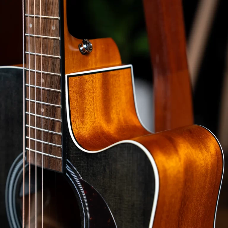 Close-up of a sunburst acoustic guitar showing the body, cutaway, and strings with a dark soundhole in the foreground ขายราคาพิเศษ