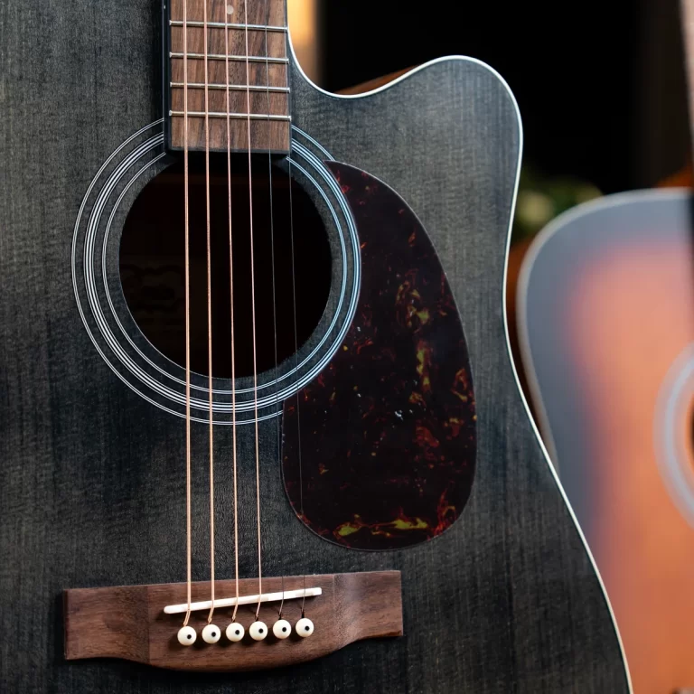 Close-up of a dark wood acoustic guitar focusing on the soundhole, strings, and bridge. ขายราคาพิเศษ