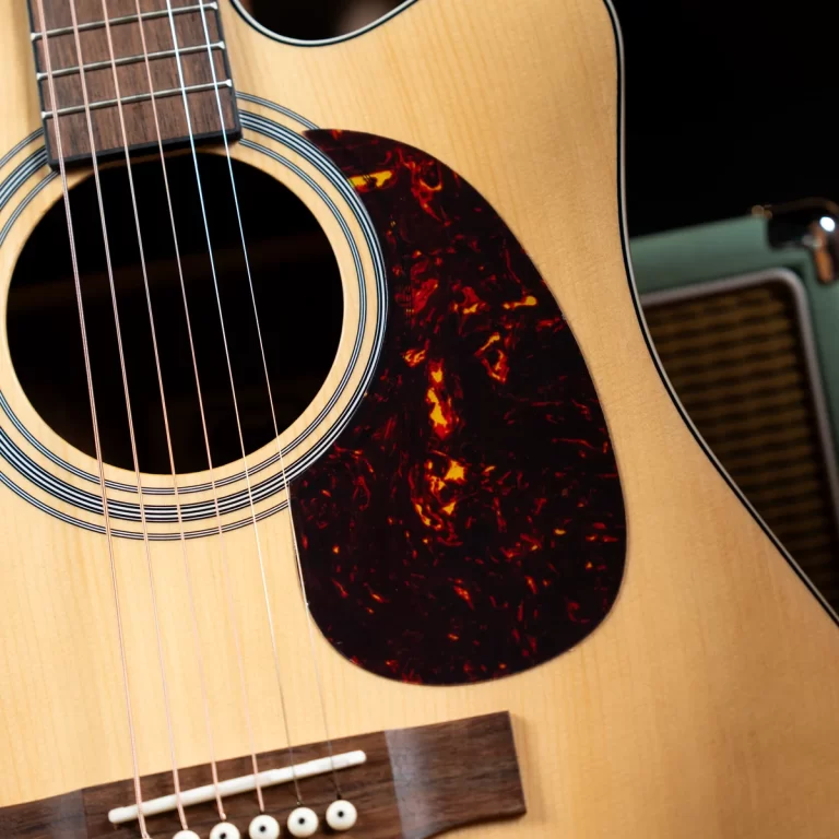 Close-up of an acoustic guitar showing the soundhole, strings, and tortoiseshell pickguard. ขายราคาพิเศษ