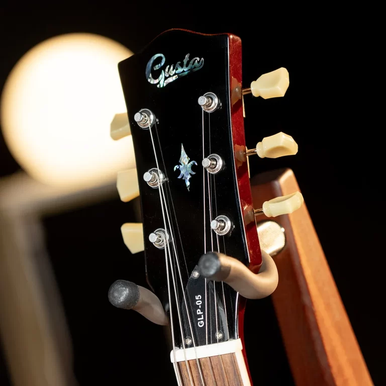 Close-up of a black guitar headstock with six cream tuners, strings, and the Gusta logo; model GLP-05 visible on the neck edge. ขายราคาพิเศษ