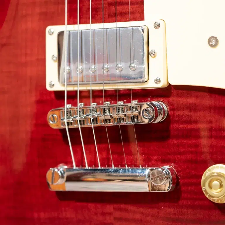 Close-up of a red electric guitar showing a chrome bridge, pickup, and strings over a glossy finish. ขายราคาพิเศษ