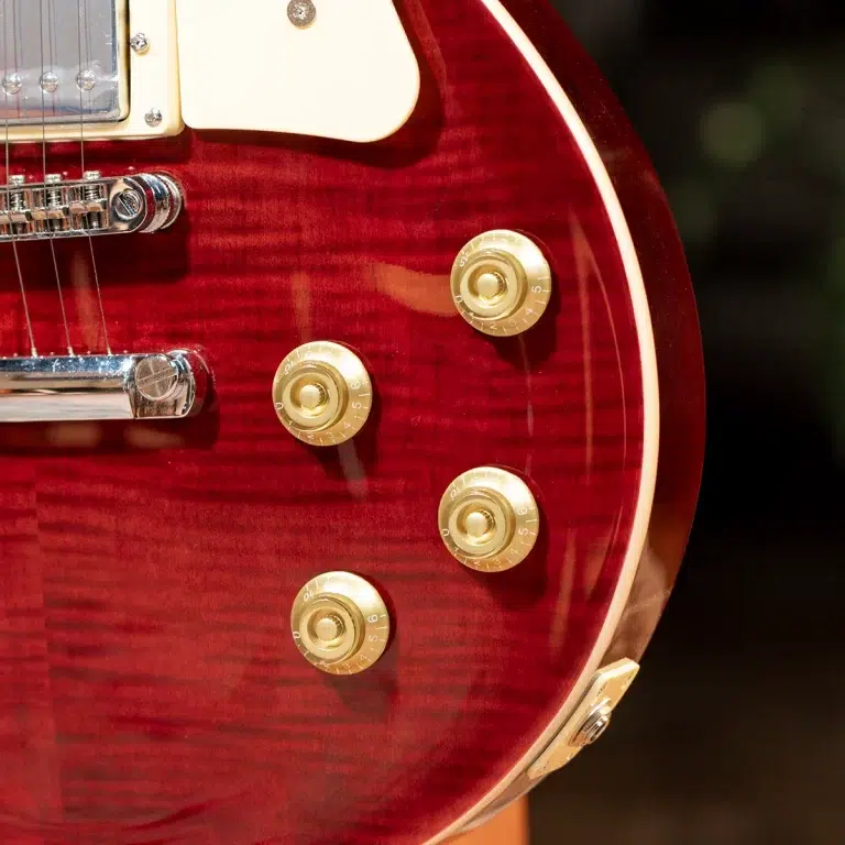 Close-up of a glossy red electric guitar body showing gold control knobs and chrome hardware. ขายราคาพิเศษ