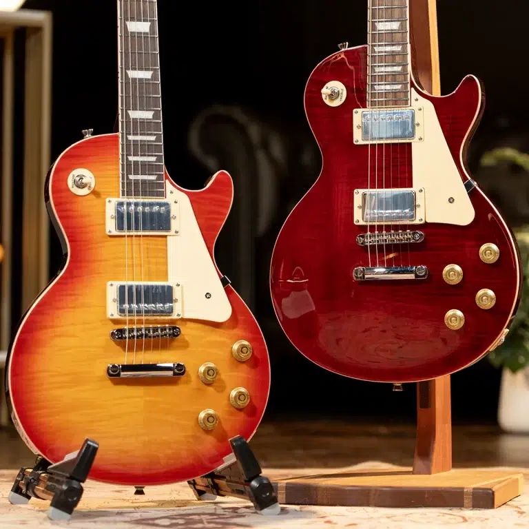 Two electric guitars on stands—one sunburst finish, the other solid red with a cream pickguard, indoors on a wooden floor. ขายราคาพิเศษ
