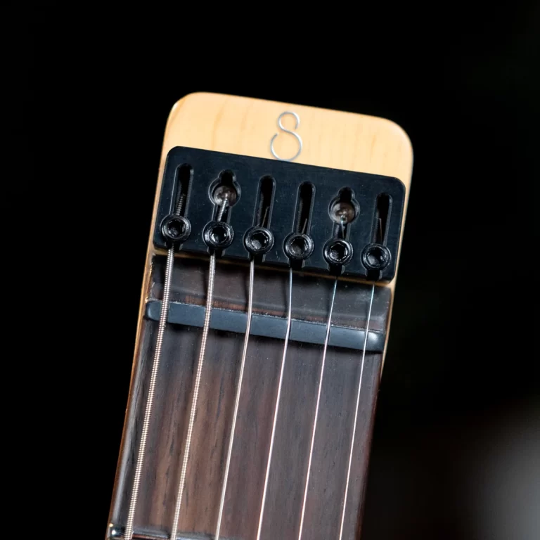 Close-up of a guitar headstock showing six strings and the nut against a black background. ขายราคาพิเศษ