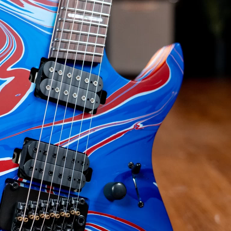 Close-up of a blue electric guitar with red and white flame graphics, showing the pickups and strings close to the body. ขายราคาพิเศษ