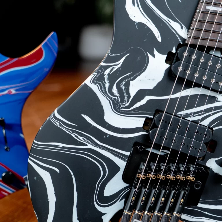 Close-up of a black electric guitar with a white marbled finish, showing pickups and strings. ขายราคาพิเศษ