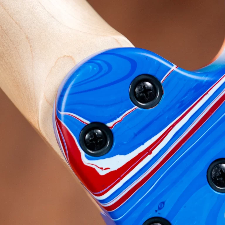 Close-up of a blue electric guitar body with red and white stripes, screws, and a wooden neck in the background. ขายราคาพิเศษ
