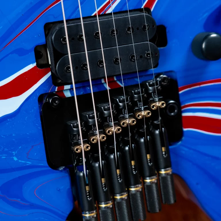 Close-up of a blue electric guitar showing the black dual-humbucker pickup and six-string bridge with gold saddles. ขายราคาพิเศษ