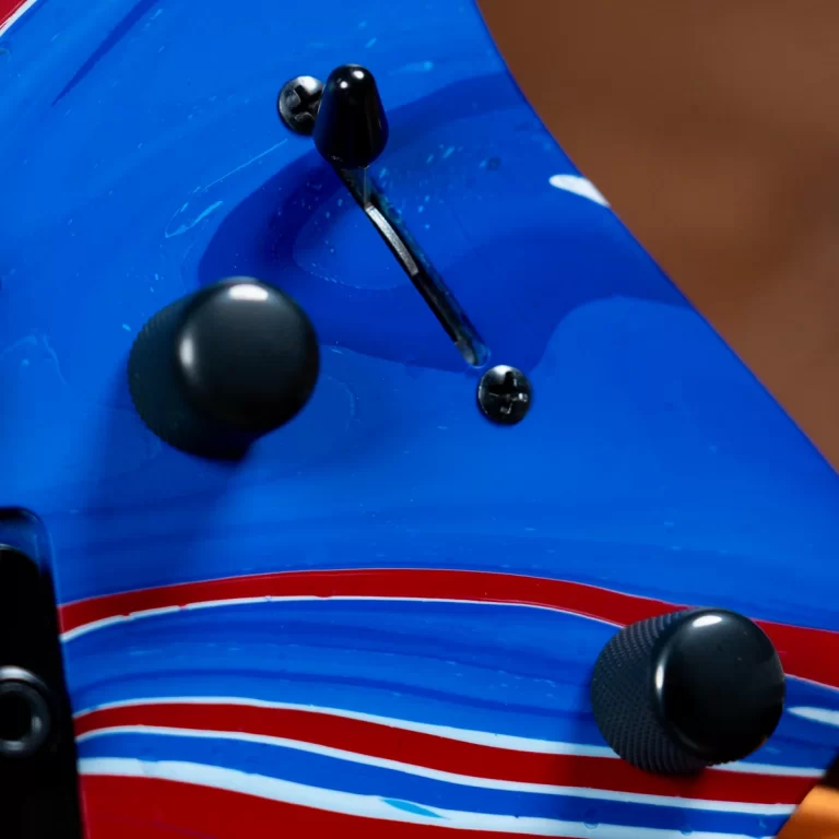 Close-up of an RC boat hull: blue surface with red/white stripe and black control levers. ขายราคาพิเศษ