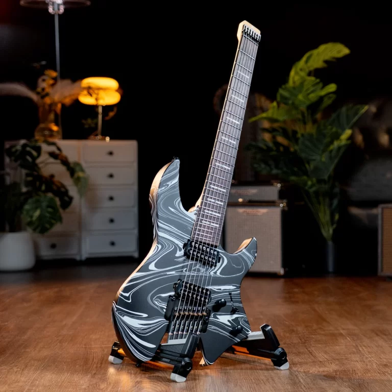 Electric guitar with a gray marble finish on a stand in a dimly lit studio with amps and plants in the background. ขายราคาพิเศษ