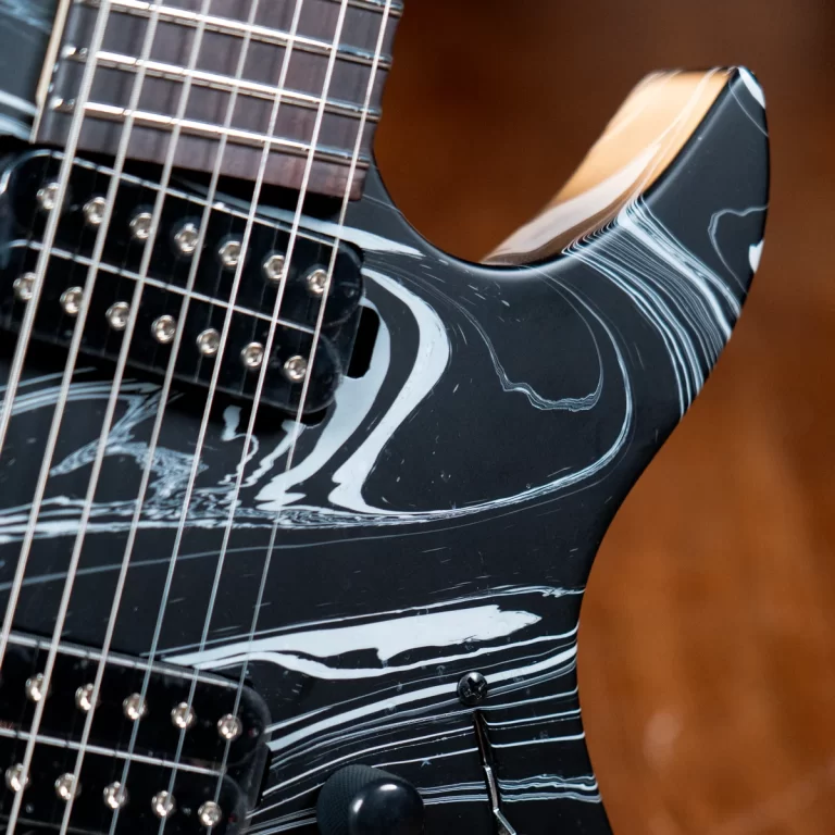 Close-up of an electric guitar with a black marbled body, strings, and pickups visible near the neck. ขายราคาพิเศษ