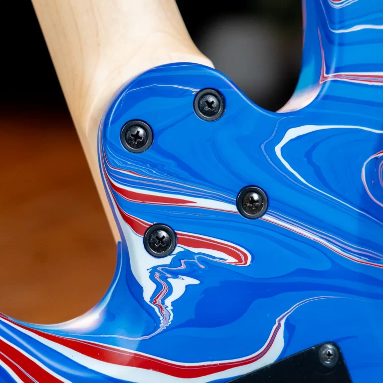 Close-up of a blue electric guitar body with red and white swirls and black screw ferrules. ขายราคาพิเศษ
