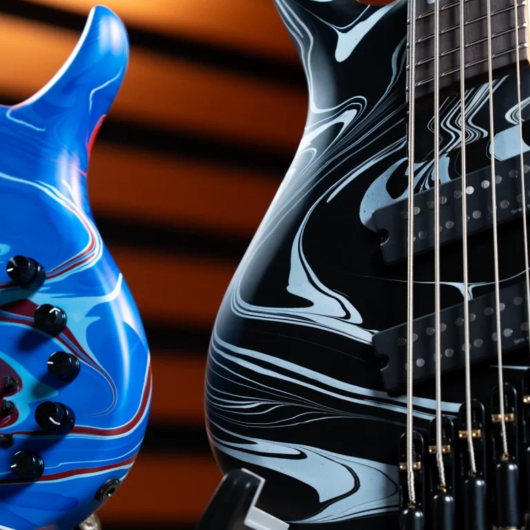 Two electric guitars closely framed: a blue swirled body on the left and a black marbled guitar with strings and pickups on the right ขายราคาพิเศษ