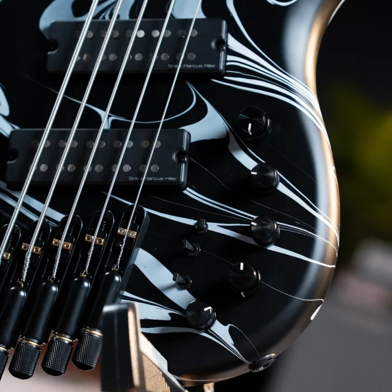 Close-up of a black electric bass guitar with white striped flame patterns, showing strings, pickups, and control knobs. ขายราคาพิเศษ
