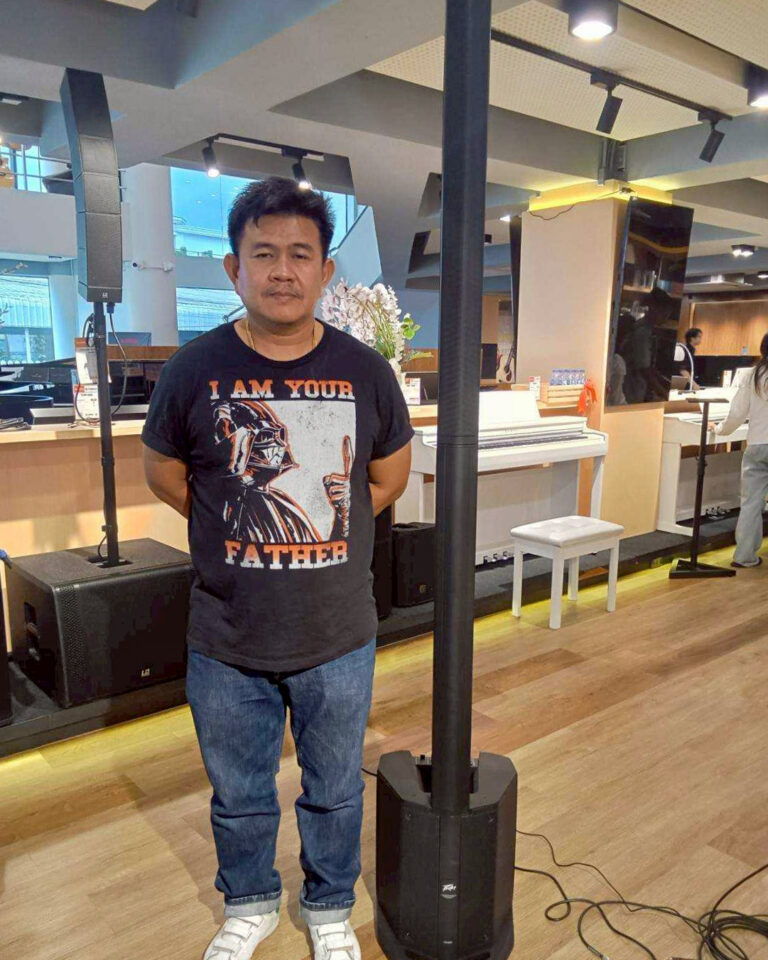 Man wearing a Star Wars T-shirt that says 'I am your father' stands with hands behind back in a modern indoor space with audio equipment nearby.
