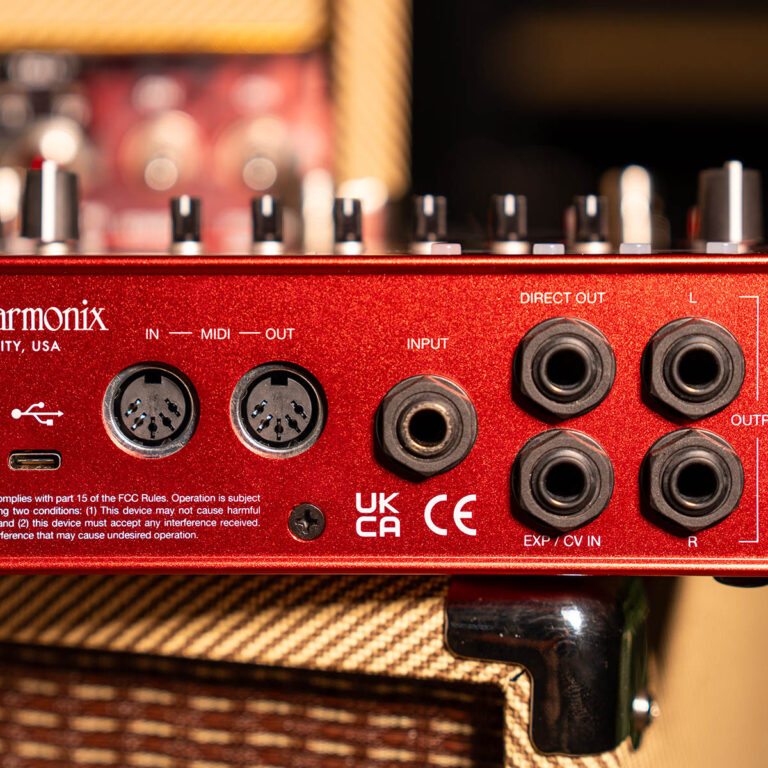 Close-up of a red metal audio interface back panel with multiple input/output jacks labeled IN, MIDI, OUT, INPUT, DIRECT OUT, and EXP/CV IN on a wooden cabinet. ขายราคาพิเศษ