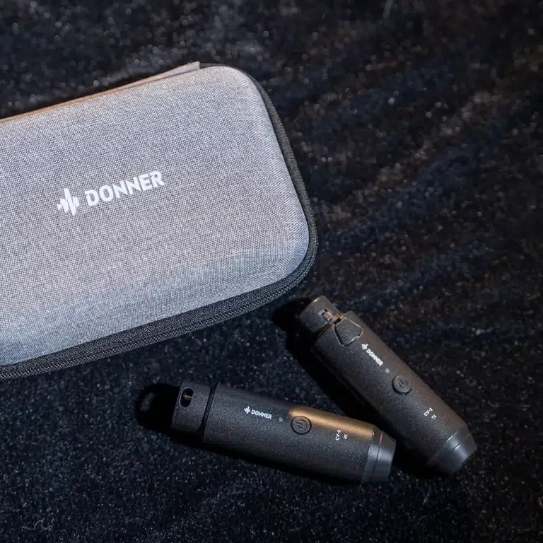 Grey DONNER carrying case with two black wireless guitar transmitters on a dark textured surface with subtle light reflections. ขายราคาพิเศษ